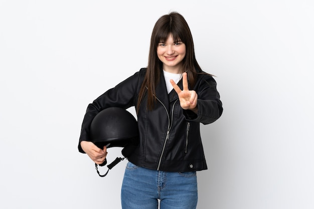 Woman holding a motorcycle helmet isolated on white wall smiling and showing victory sign