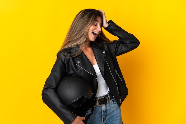 Woman holding a motorcycle helmet isolated on yellow smiling a lot