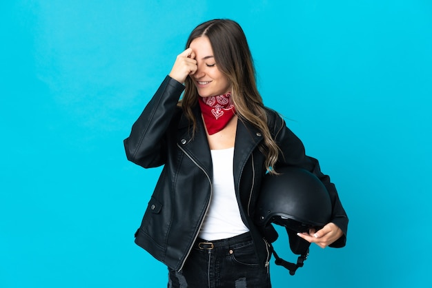 Женщина, держащая мотоциклетный шлем позирует изолированной у глухой стены