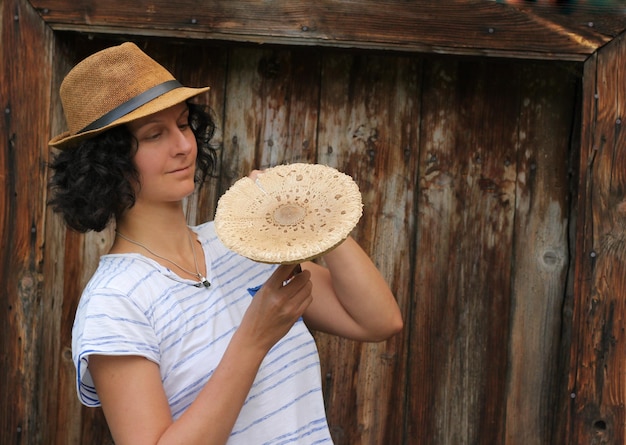 Photo woman holding mushroom while standing against wood