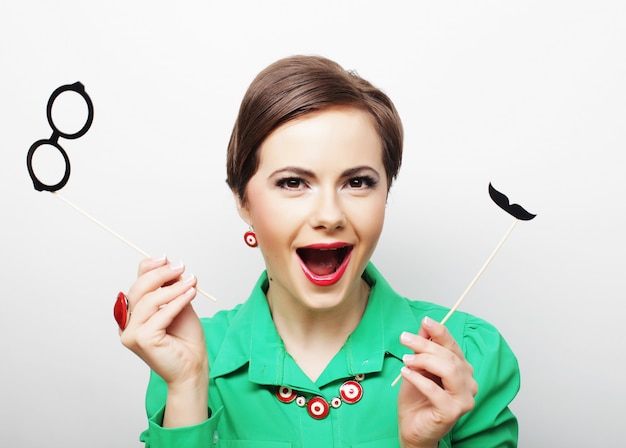 Woman holding mustache and glasses on a stick.