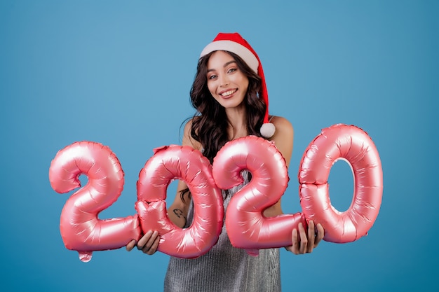 Woman holding new year balloons wearing santa hat and dress