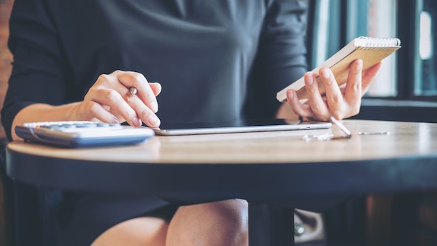 woman holding notebook and using tablet