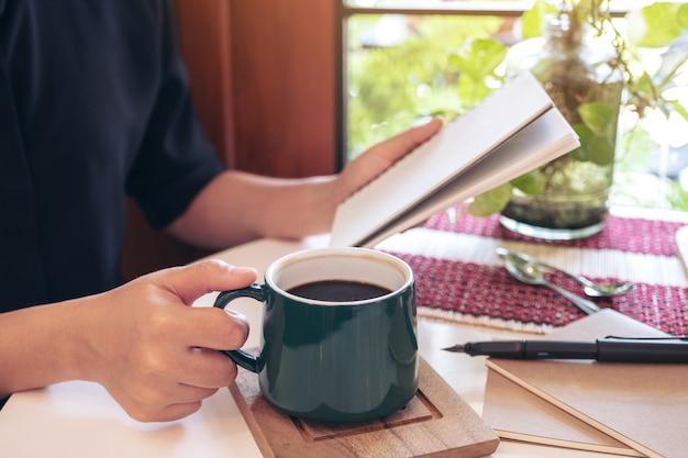 コーヒーを飲みながらノートを保持している女性