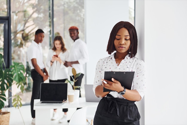 Woman holding notepad Group of african american business people working in office together