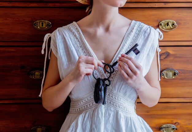 Woman holding old key aind lock n a hands and stay near window with natural light