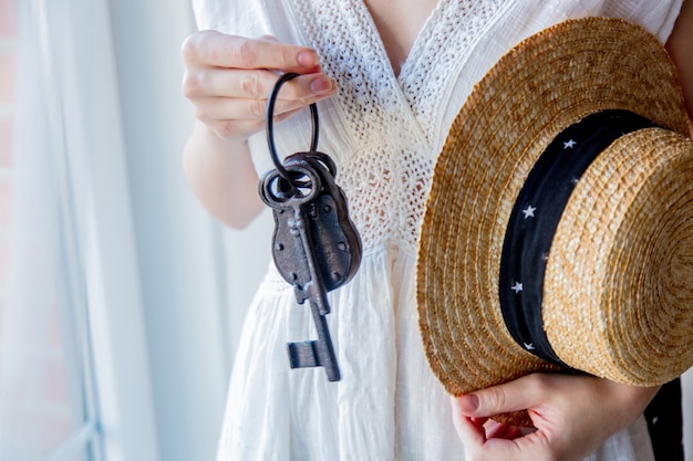 Woman holding old key and lock in a hands and stay near window with natural light