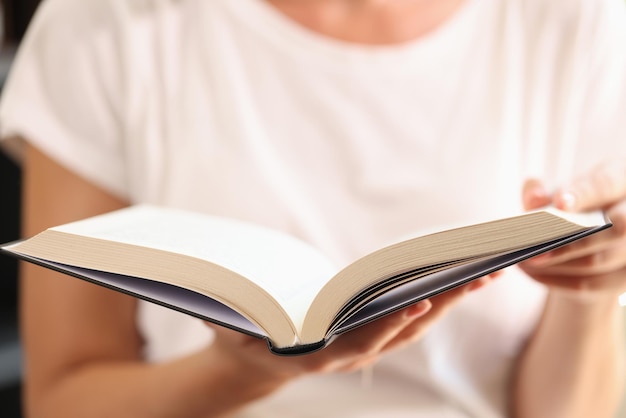 Woman holding open book in her hands close up shallow depth of field