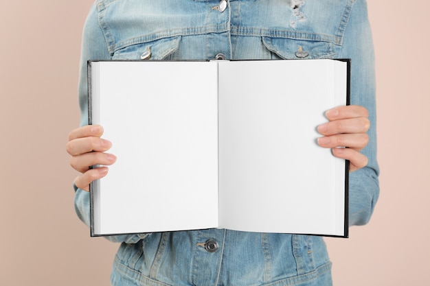 Woman holding open book with blank pages on pink