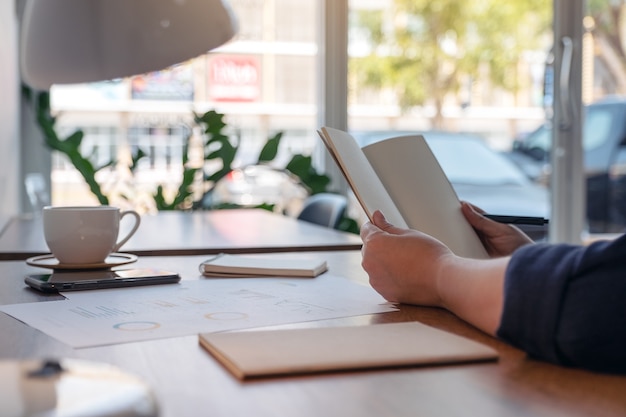 woman holding and opening a blank notebook on wooden table