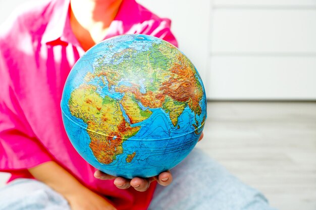 Photo woman holding out physical globe