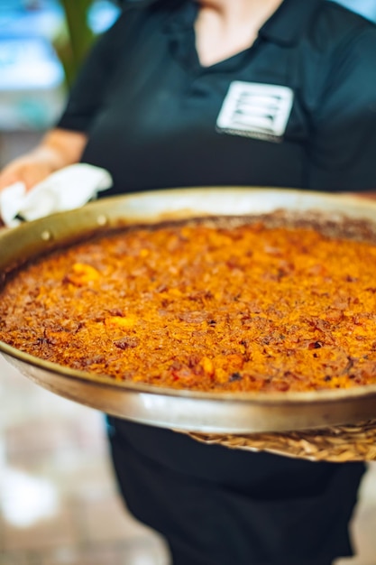 A woman holding a pan of paella.