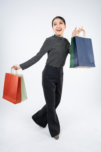 Woman holding paper bags with smile on white background in shopping concept.