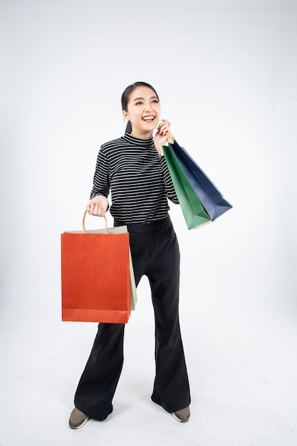 Woman holding paper bags with smile on white background in shopping concept.