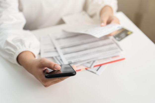 Woman holding paper bill invoice and mobile phone