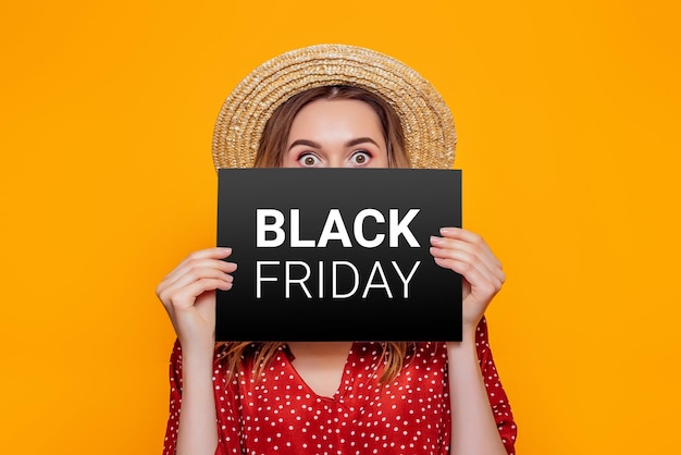 Photo woman holding paper poster with black friday isolated on an orange studio background