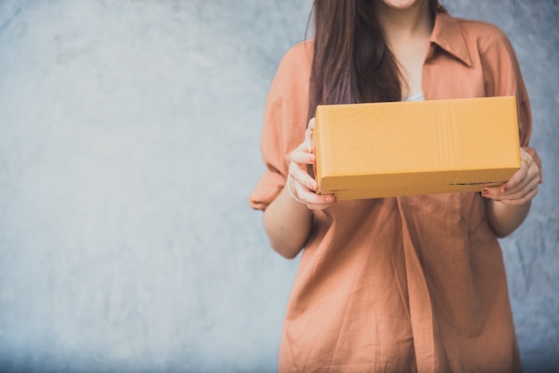 ロジスティックサービスで顧客に配達するための小包ボックスを保持する女性