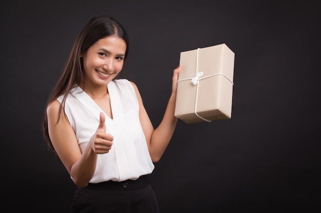 Woman holding parcel box, pointing thumb up