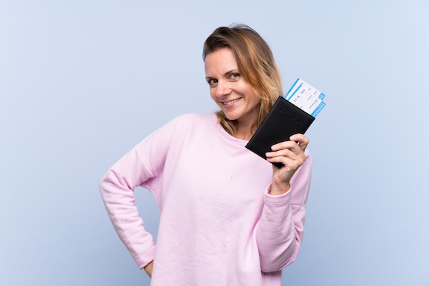 Woman holding a passport over blue wall