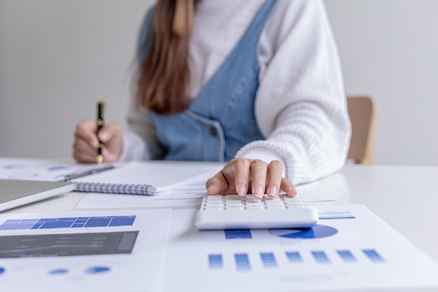 机の上の書類を指すペンを持っている女性は、財務学者であり、会社の財務書類の正確性をチェックしてから、幹部に提示しています。会計監査の概念。