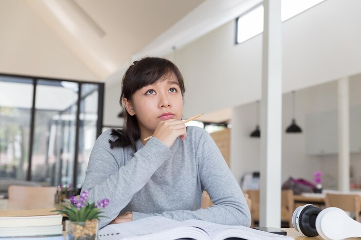 Photo テーブルの上の本の上に筆を握っている女性