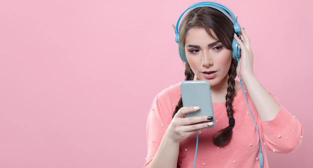 Woman holding phone and listening to music on headphones