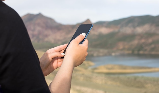 自然の背景で携帯電話を握っている女性