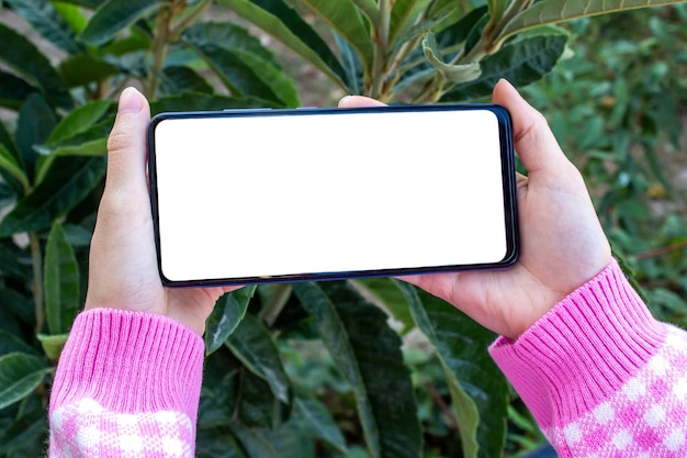 Woman holding phone with blank white mockup screen