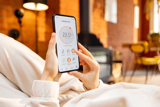 Woman holding phone with running smart home application for temperature control