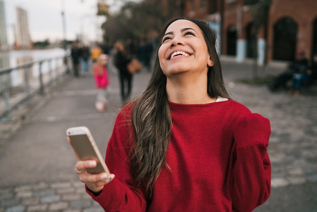 Woman holding phone with successful expression.