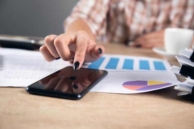 Woman holding phone and working chart report