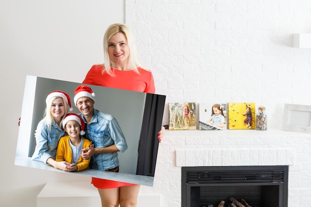 Photo woman holding a photo canvas with a picture of christmas.