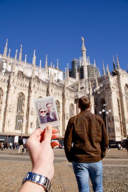 woman holding photograph of couple by church