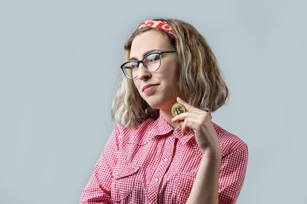 Woman holding a physical bitcoin cryptocurrency in her hand on gray background