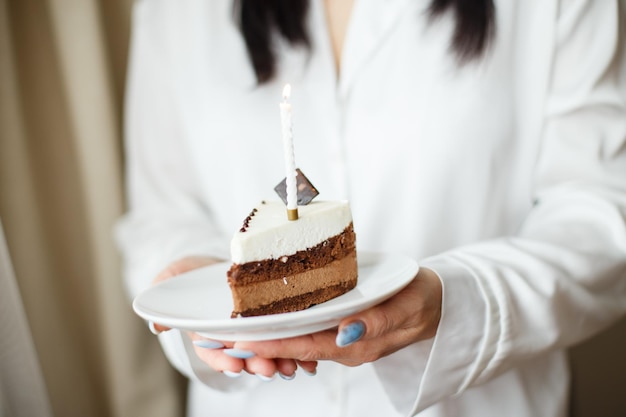 Woman holding piece of cake with a candle