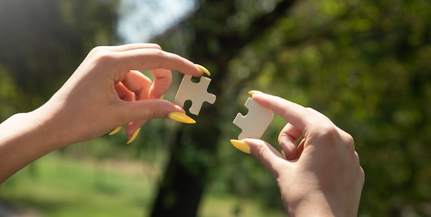 Woman holding a piece of wooden jigsaw puzzle together in the outdoors