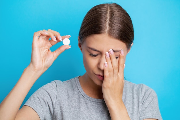 Woman holding pill and glass water taking medicine from headache stomach pain or taking vitamins