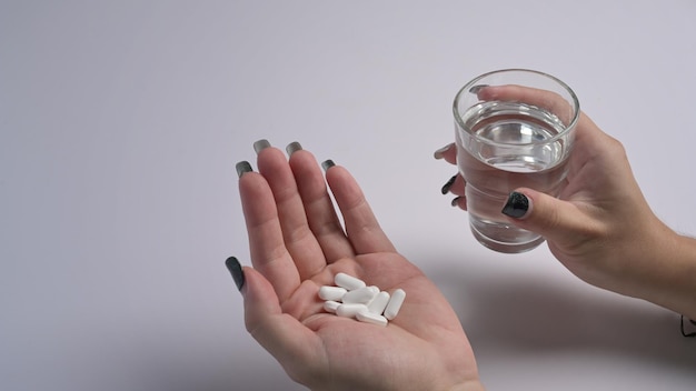 Woman holding pills and a glass of water in hand Healthcare medicine treatment therapy concept