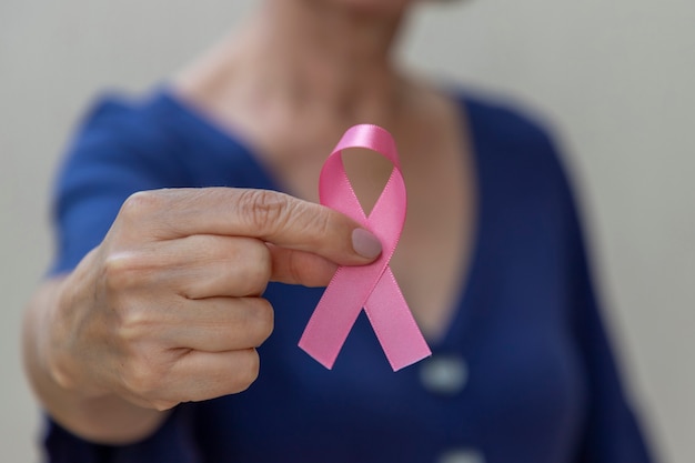 Woman holding pink bow in her hand. Breast cancer prevention campaign. Pink October