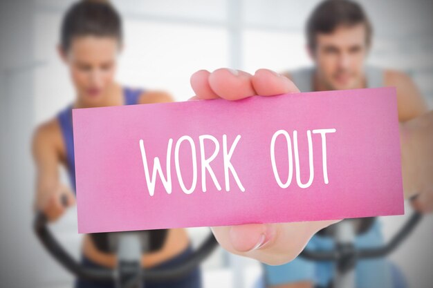 Woman holding pink card saying work out against fitness class in gym