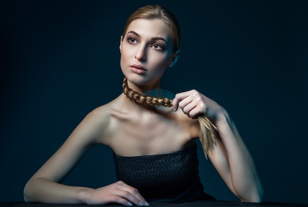 Woman holding plait around her neck. Horizontal studio shot