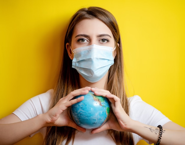 woman holding planet earth globe wearing mask