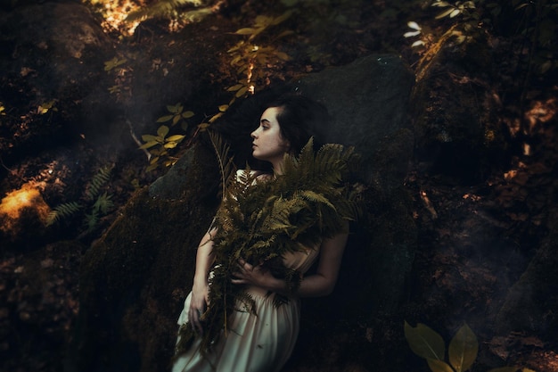 Woman holding plant in forest at night