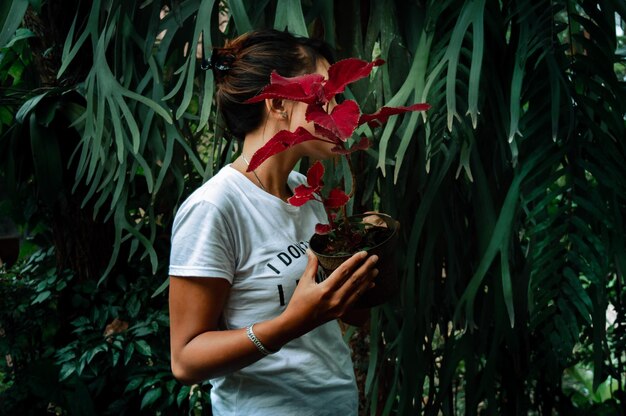 Photo woman holding plant standing by tree