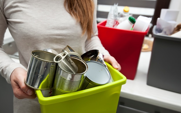 Woman holding a plastic bin with metal garbage