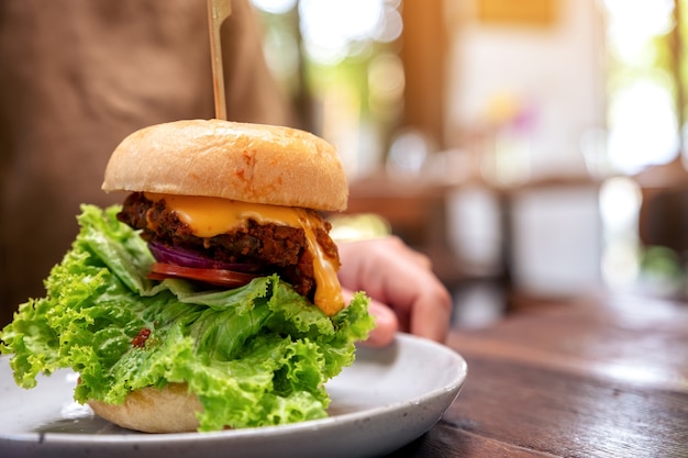 Woman holding a plate of beef hamburger on wooden table in the restaurant