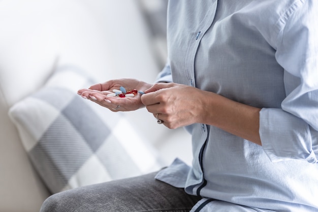 Woman holding plenty of colorful pills in her hand.