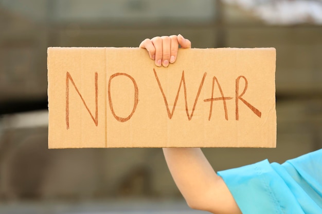 Woman holding poster with words No War outdoors closeup