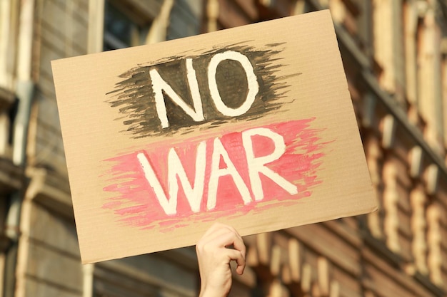 Photo woman holding poster with words no war outdoors