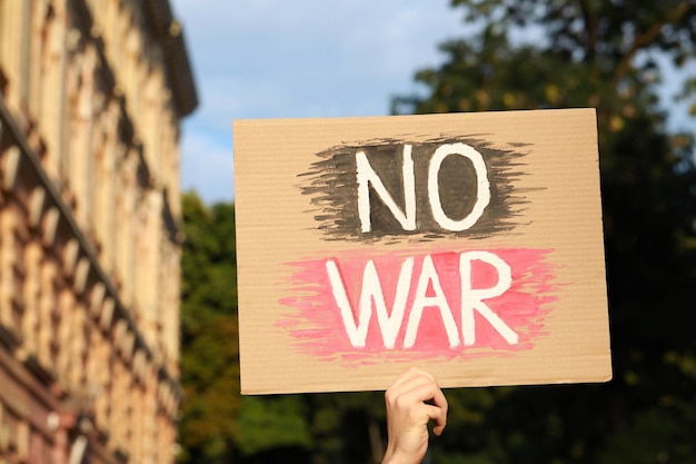 Photo woman holding poster with words no war outdoors